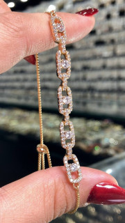 تصویر نمای نزدیک دستبند مارشالی ژوپینگ اورجینال مدل مسیکا با آبکاری طلایی، زنجیر ونیزی حلقههای مستطیلی نگیندار و نگینهای درخشان مرکزی